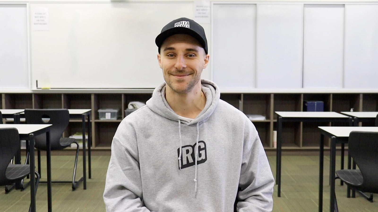 Man sitting in a classroom in front of a whiteboard.