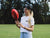 Female wearing a black hat handballing an AFL football.