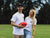 Male and female smiling, holding an AFL football.