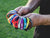 Holding a handful of colourful AFL football club wristbands.